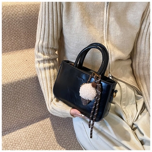 Dettaglio borsa in pelle cerata nera con ciondolo peluche gelato su scale morbide