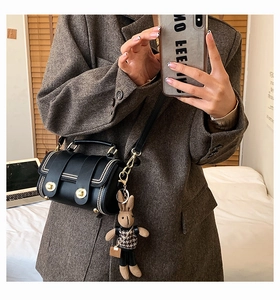 Detail of black crossbody bag featuring golden CC lock and brown bunny charm accessory