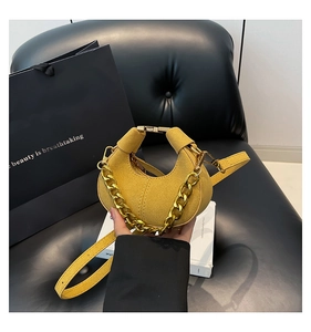 Detalle del bolso medialuna de ante amarillo con cadena dorada y correa de cuero