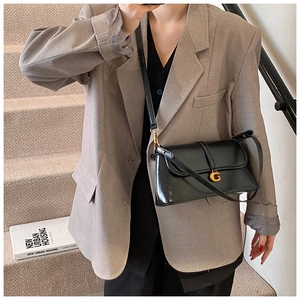 Detail of a black glossy leather crossbody bag with a golden G-logo metal buckle