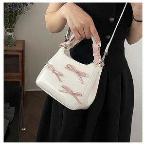 Detailed view of a white PU leather crossbody bag with cute pink ribbon bow accents