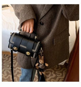 Detailed view of a black leather handbag with gold rivets and a cute rabbit charm