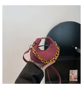 Detalle de bolso hobo granate con cadena dorada y textura de gamuza mate suave