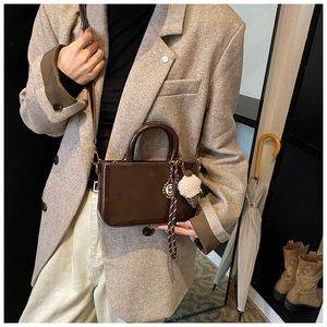 Borsa a mano in pelle cerata marrone indossata con blazer grigio per un look professionale