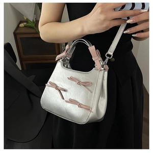 Detail of silver metallic bag featuring pink satin bows and a detachable shoulder strap