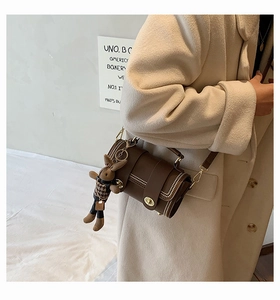 Brown leather cylinder bag with gold turn-lock and cute houndstooth bunny charm detail