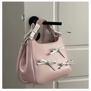 Detail of pink bow-knot handbag hanging on door handle showing texture and strap
