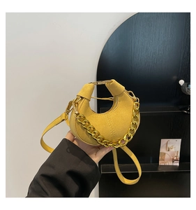 Detalle del bolso de media luna jengibre con asa de cadena dorada y textura de ante