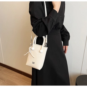 Detail of white leather crossbody bag featuring distinctive double ball handle and COIN 2DN print