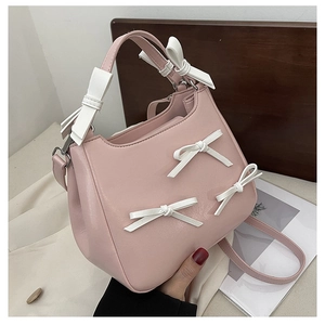 Detail of pink crossbody bag with white bow accent and round top handle in close-up
