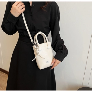 Detail of off-white leather phone bag with knots decor on a model in black outfit