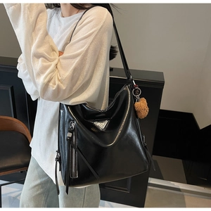 Close-up of black glossy PU tote bag featuring a silver triangle metal plaque and teddy charm