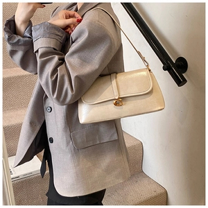 Detail of cream underarm bag with golden G-buckle closure and pearl finish leather