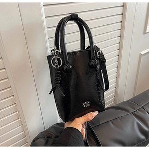 Detailed view of black oiled leather texture and silver COIN 2DN lettering on a tote bag