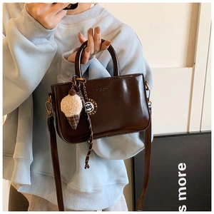Détail du sac à main en cuir synthétique marron avec breloque peluche et bandoulière