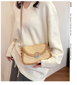 Detailed close-up of woven straw crossbody bag with leather trim and silver metal buckle
