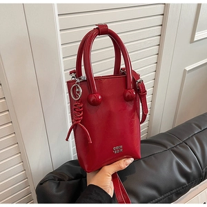 Detail of red oil wax leather handbag featuring silver letters and spherical handle decor