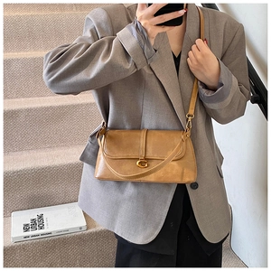 Detail of vintage brown leather baguette bag with golden G buckle and shoulder strap