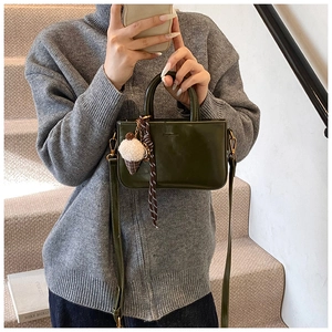 Dettaglio della borsa in pelle verde scuro con ciondolo pompon e decorazione in seta