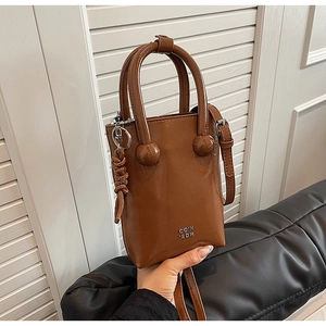 Close-up of brown glossy oil-wax leather texture with metal logo and handle details