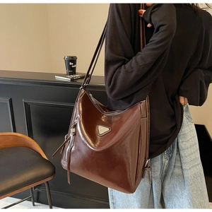 Detail view of large dark brown leather tote bag with silver metal triangle ornament