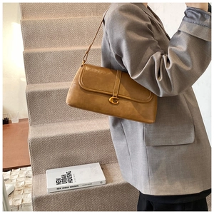 Close-up of vintage brown underarm bag featuring a metallic gold letter G buckle detail