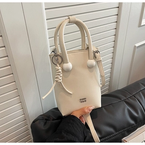 Detail of white PU leather crossbody bag featuring spherical handle decor and brand logo