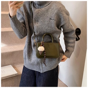 Mini sac carré en cuir ciré vert olive avec pendentif en peluche sur un escalier