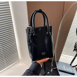 Detail of glossy black oil wax leather handbag with silver COIN 2DN logo and knot charm