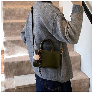Détail du sac en cuir huilé vert avec breloque peluche glace et décor tressé