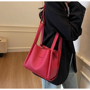 Detail view of fuchsia bucket bag with lychee texture and brand logo