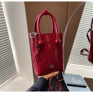 Detail view of red oil wax leather handbag with ball handles and woven charm