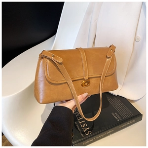 Detailed view of brown leather shoulder bag with vintage gold G-shaped metal buckle closure