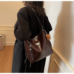 Macro shot of dark brown glossy leather tote bag with silver zipper and triangle logo