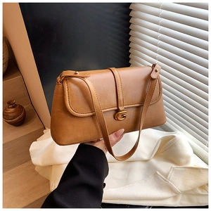 Detail shot of caramel leather underarm bag with golden G clasp against soft lighting