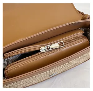 Detail of smooth metal zipper and geometric pattern lining on a woven crossbody bag