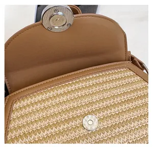 Close-up of woven straw handbag with brown leather trim and silver magnetic snap closure