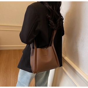 Detailed view of dark brown litchi grain leather bucket bag with reinforced stitching