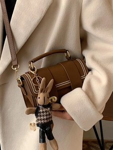Brown leather handbag with metal rivets and cute knit rabbit pendant accessory