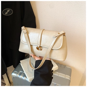 Close-up of beige underarm bag featuring a golden G-clasp and fine leather texture