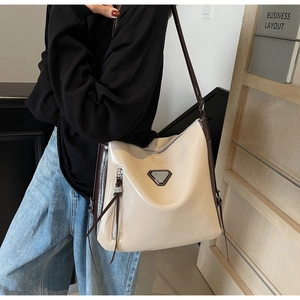 Detail of beige hobo bag with side zipper tassel and triangular metallic decor