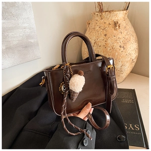 Dettaglio della borsa in pelle cerata con corda intrecciata e ciondolo in peluche su blazer