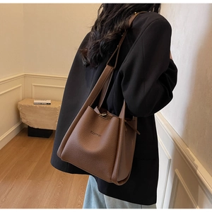Brown lychee grain bucket bag carried by a model in a minimalist French interior style