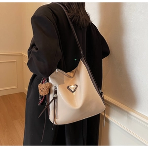 Detail of beige patent leather tote with metal logo and cute plush bear charm