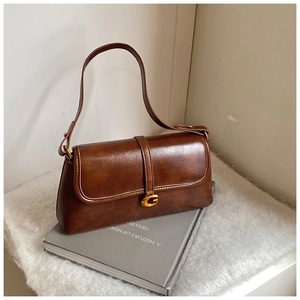 Detailed close-up of vintage brown leather underarm bag with gold G metal clasp and strap