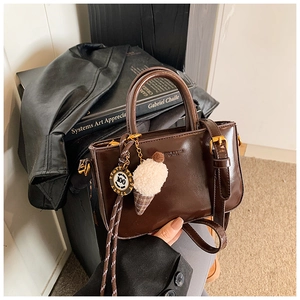 Dettaglio borsa marrone in pelle cerata con goffratura moda e ciondolo a gelato peluche