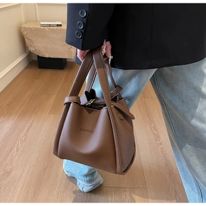 Detailed macro view of high-quality brown lychee grain leather on a stylish bucket handbag