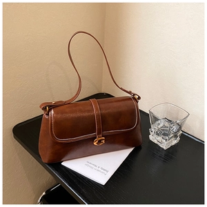 Detail of vintage brown gloss leather bag featuring a gold metallic G-shaped buckle