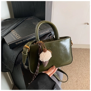 Borsa a mano verde scuro in pelle cerata con ciondolo di peluche e nastro elegante