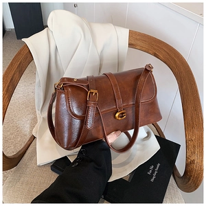 Close-up of brown vintage leather bag with gold G logo and metallic hardware on a chair